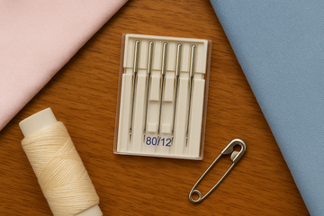 Image of pack of 80/12 sewing needles, with thread and safety pin